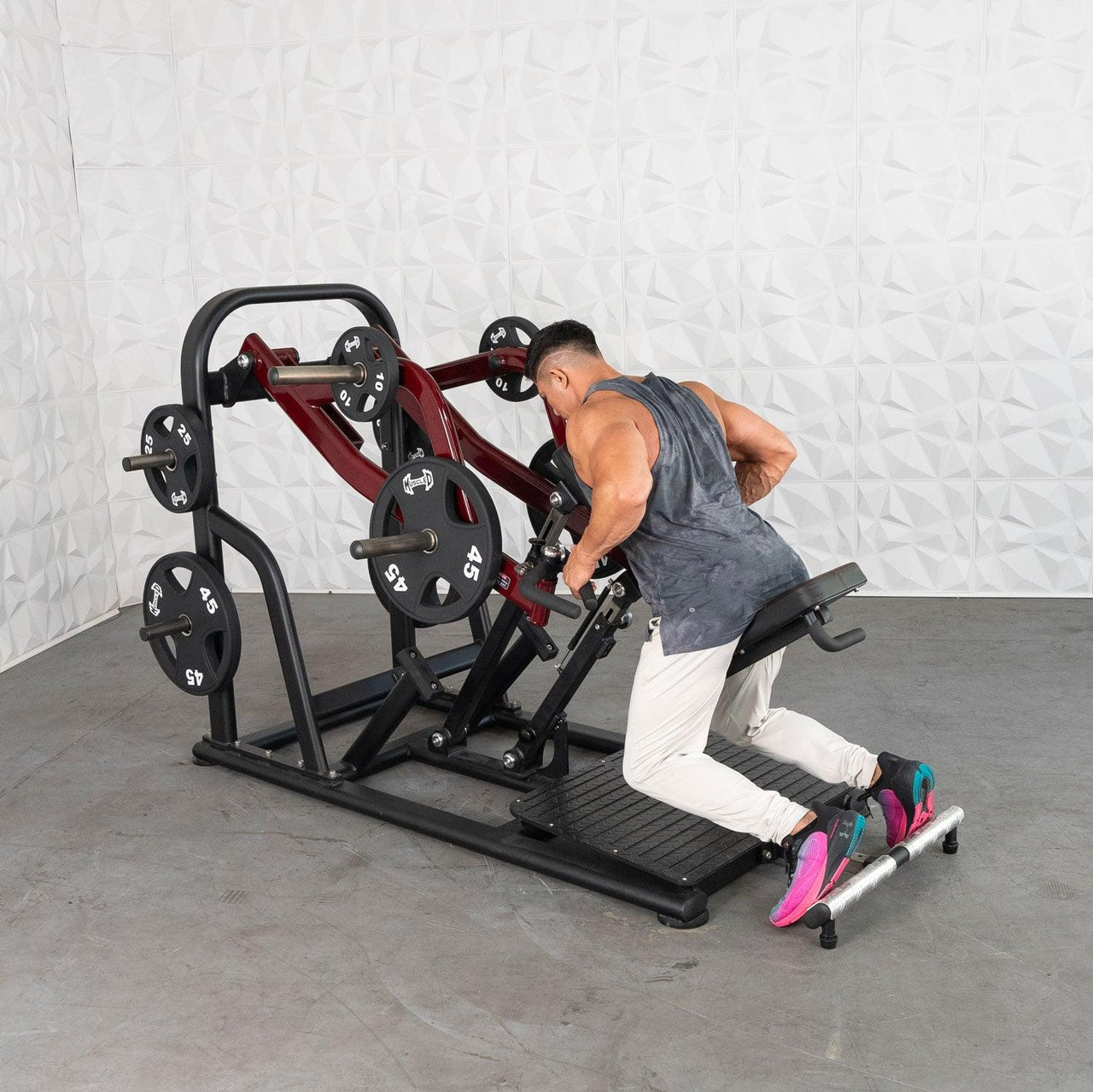 Man using a red and black chest-supported plate-loaded row machine with 45lb plates.