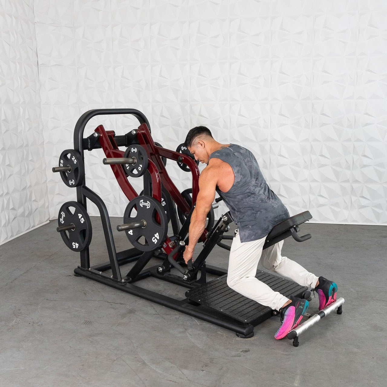 Man using a red and black chest-supported plate-loaded row machine in a gym.