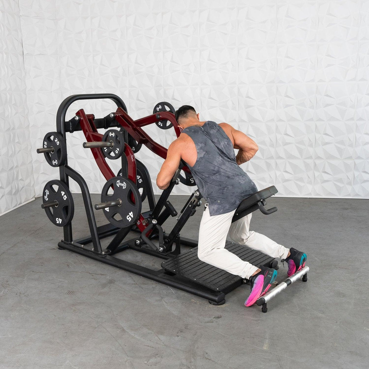 Man using a red and black chest-supported plate-loaded row machine.