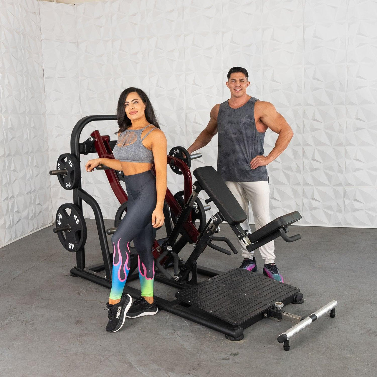 Man and woman standing next to a black and red plate-loaded chest-supported row machine.