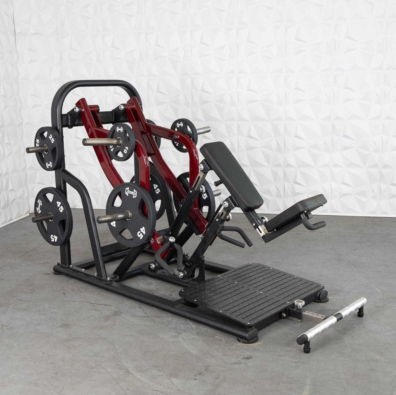 Red and black plate-loaded chest-supported row machine with weight plates on a gray floor.