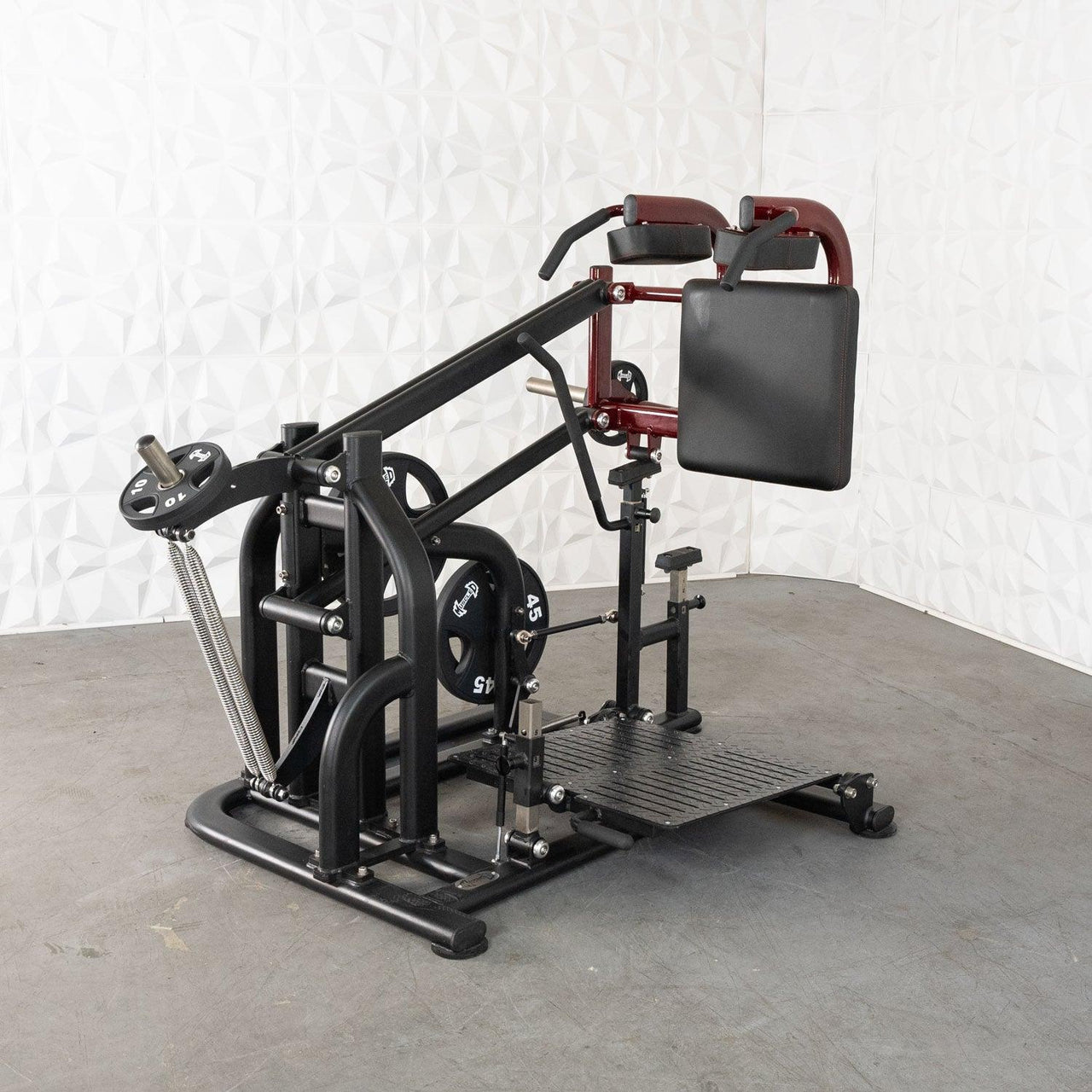 Black and maroon plate-loaded squat machine with a textured footplate and padded backrest.