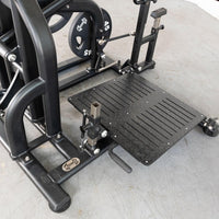 Thumbnail for Close-up of a black plate-loaded squat machine with a textured foot platform and 45 lb weight plates.