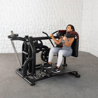 Thumbnail for Woman in athletic wear using a black plate-loaded squat machine with red shoulder pads.