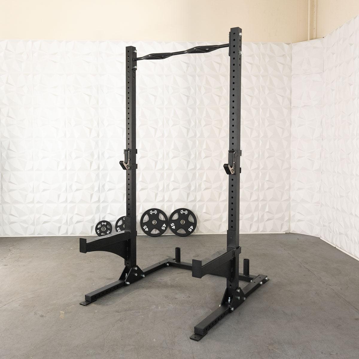 Black squat stand with pull-up bar, J-hooks, and weight plate storage, with 4 weight plates on floor.