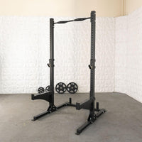 Thumbnail for Black squat stand with pull-up bar, J-hooks, and weight plate storage, with 4 weight plates on floor.