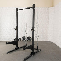 Thumbnail for Black squat stand with multi-grip pull-up bar, J-hooks, bar storage, and weight plates on a concrete floor.