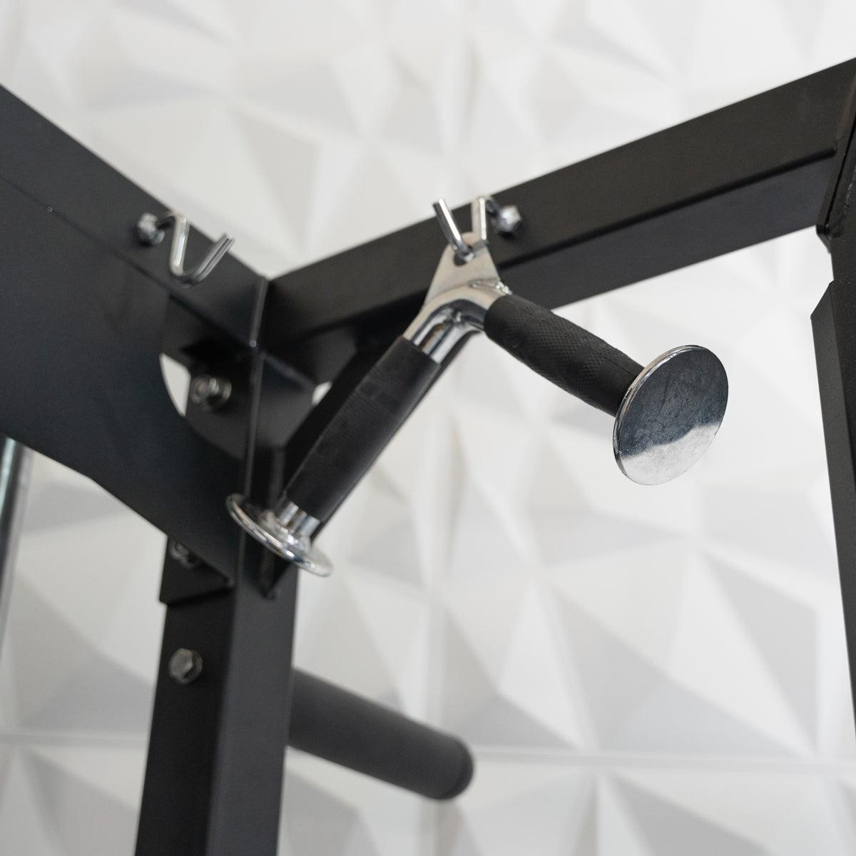 Close-up of a black fitness machine with a chrome and black rubber grip handle hanging from a hook.
