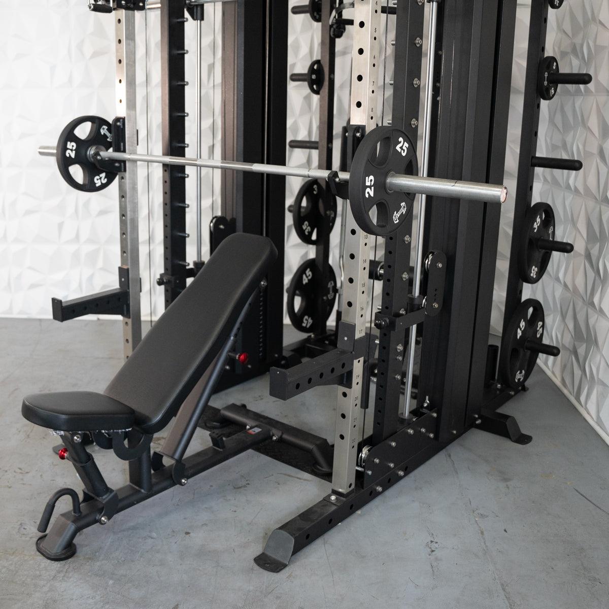 Black and silver multi-functional fitness machine with an adjustable bench and barbell loaded with 25lb plates.
