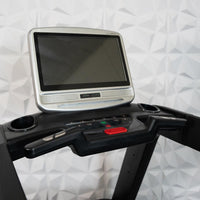 Thumbnail for Close-up of a treadmill console with a large, silver-framed touch screen and control buttons.