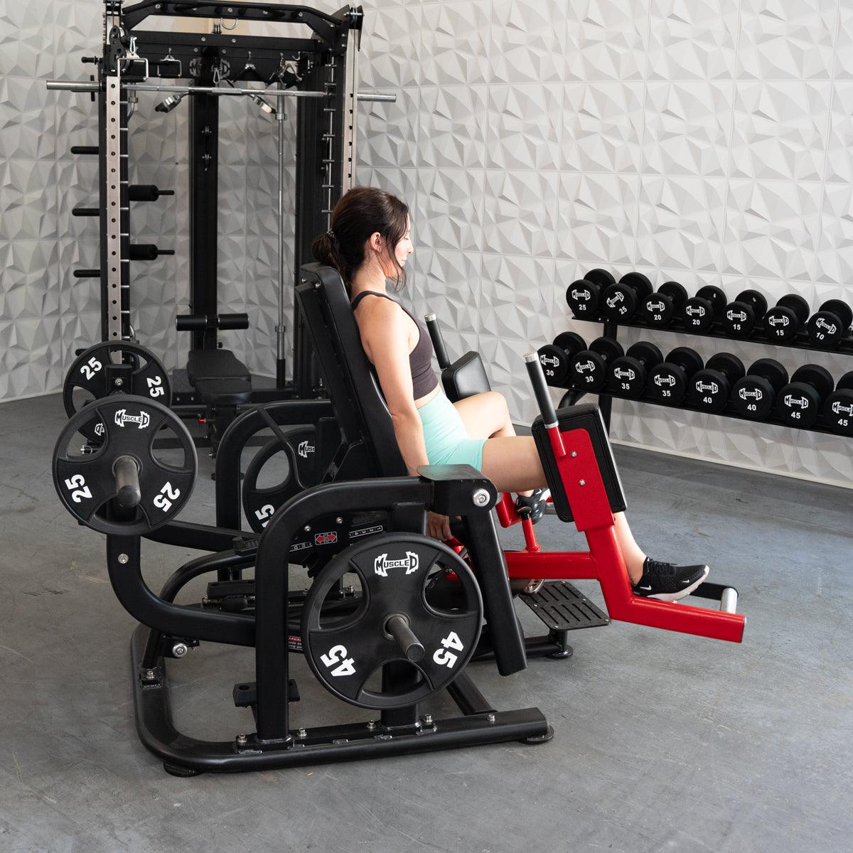 Woman using a plate-loaded abductor/hip extension machine in a gym.