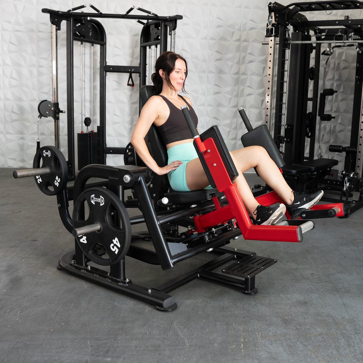 Woman using a black and red plate-loaded abductor/hip extension machine in a gym.