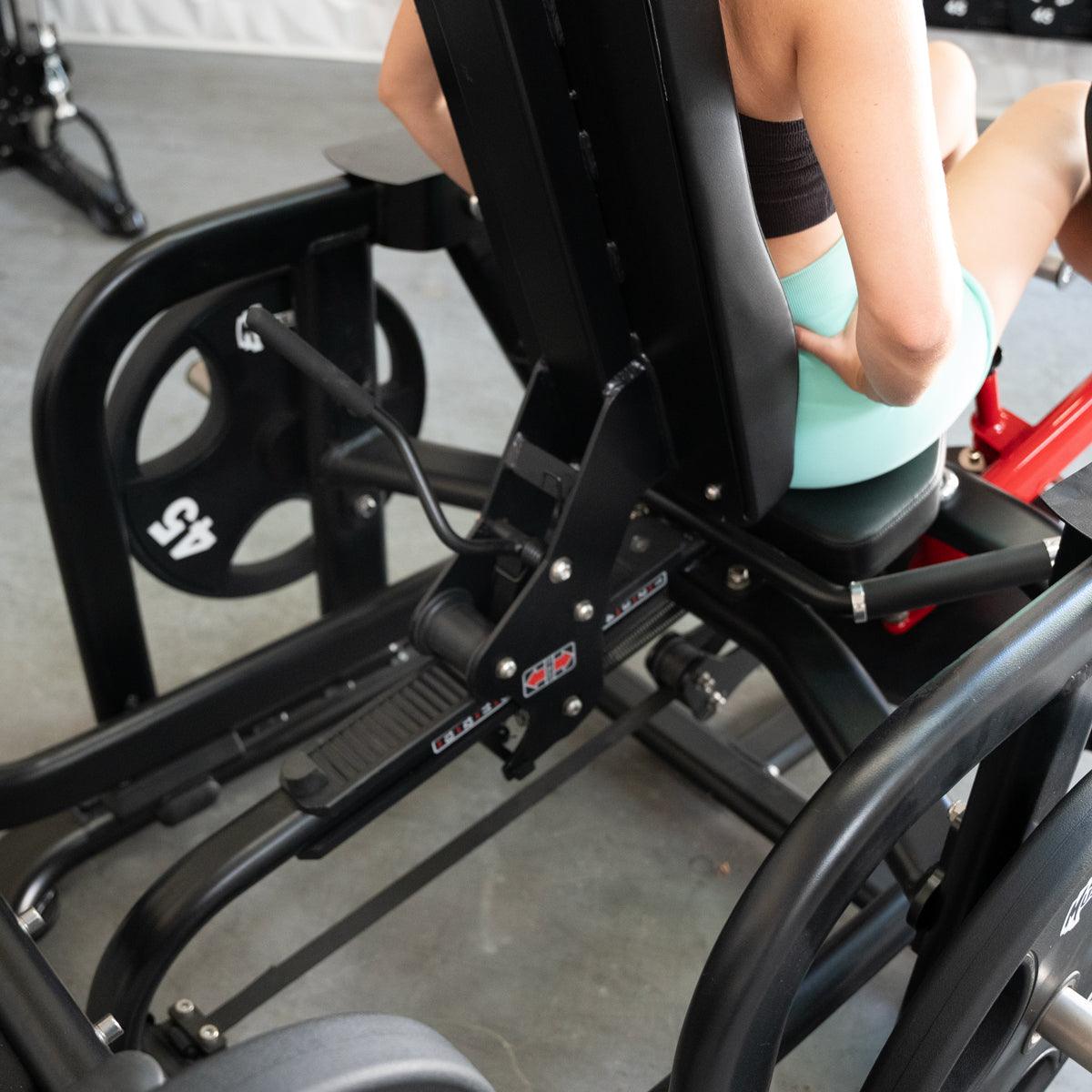Person using a black plate-loaded abductor/hip extension machine with 45lb weight plates.