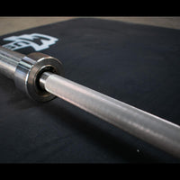 Thumbnail for Close-up of a stainless steel Olympic bar with knurling and a bearing sleeve.