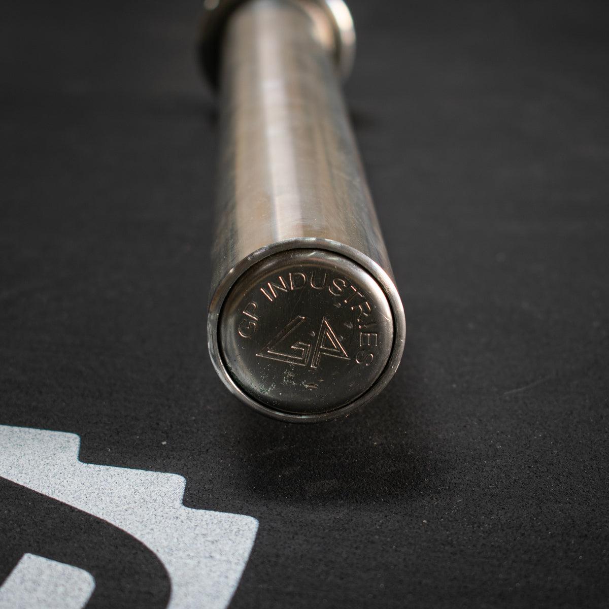 Close-up of a stainless steel Olympic bar end cap with "GP INDUSTRIES" and a logo.