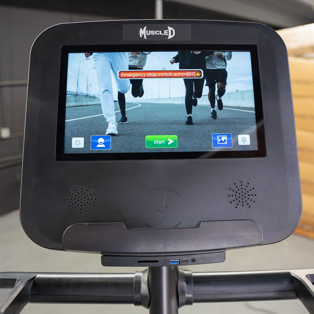 Close-up of a black stair climber console with a touchscreen displaying runners and a "start" button.