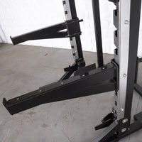 Thumbnail for Close-up of a black and silver half rack with adjustable safety bars and a vertical Olympic bar storage.