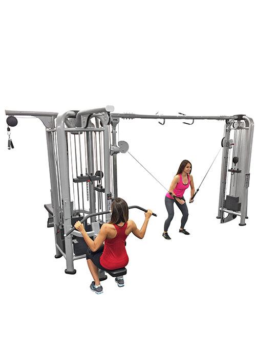 Two women using a multi-station jungle gym with lat pull-down and cable crossover functions.