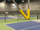 Yellow padding on a steel column and angled I-beam between indoor pickleball courts