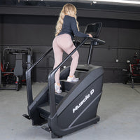 Thumbnail for Woman in athletic wear using a black Muscle D Fitness stair climber with a touchscreen in a gym.