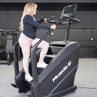 Thumbnail for Woman exercising on a black Muscle D Fitness stair climber with a touchscreen display.