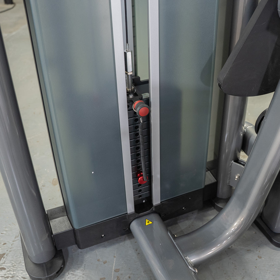 Close-up of a weight stack with a red selector pin on a commercial-grade ab crunch machine.