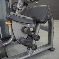 Thumbnail for Close-up of the black padded seat and armrests of an ab crunch machine with an orange adjustment lever.