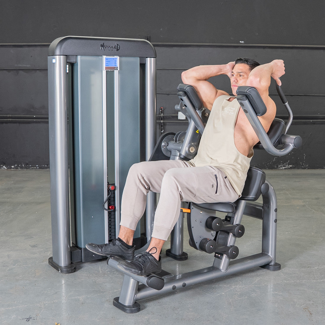 Man using a gray and black ab crunch machine in a gym.
