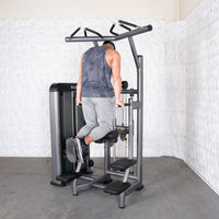 Thumbnail for Man using an assisted chin/dip machine, facing away, with his knees on the padded support.