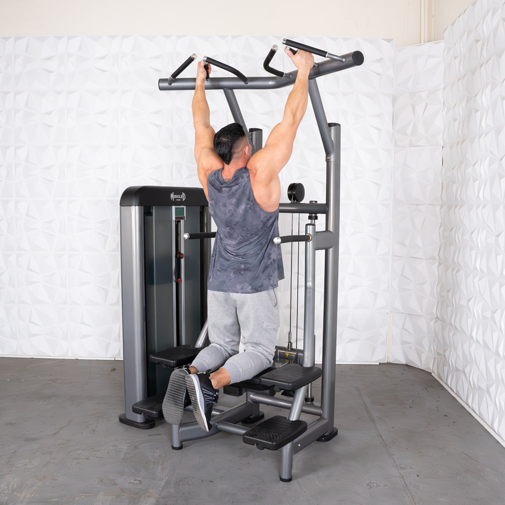 Man using a gray assisted chin/dip machine with a black weight stack, performing a chin-up.