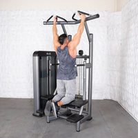 Thumbnail for Man using a gray assisted chin/dip machine with a black weight stack, performing a chin-up.