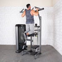 Thumbnail for Man performing assisted pull-up on a commercial-grade chin/dip machine with adjustable seat.