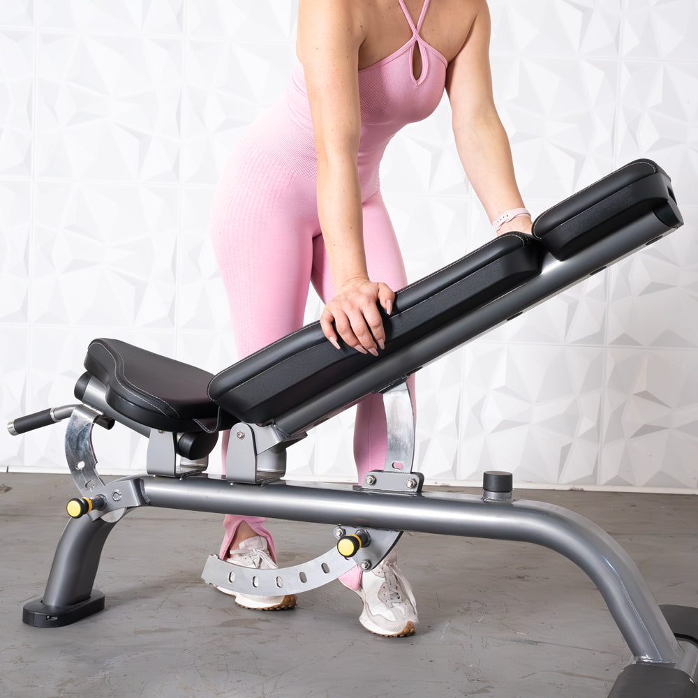 Woman in pink adjusting a gray and black adjustable weight bench.