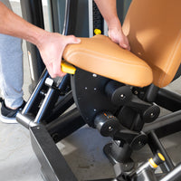 Thumbnail for Hands adjusting the tan padded seat and yellow lever of a black commercial chest press machine.