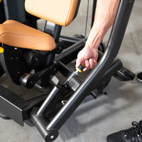 Thumbnail for Hand adjusting the seat height on a black and tan chest press machine.