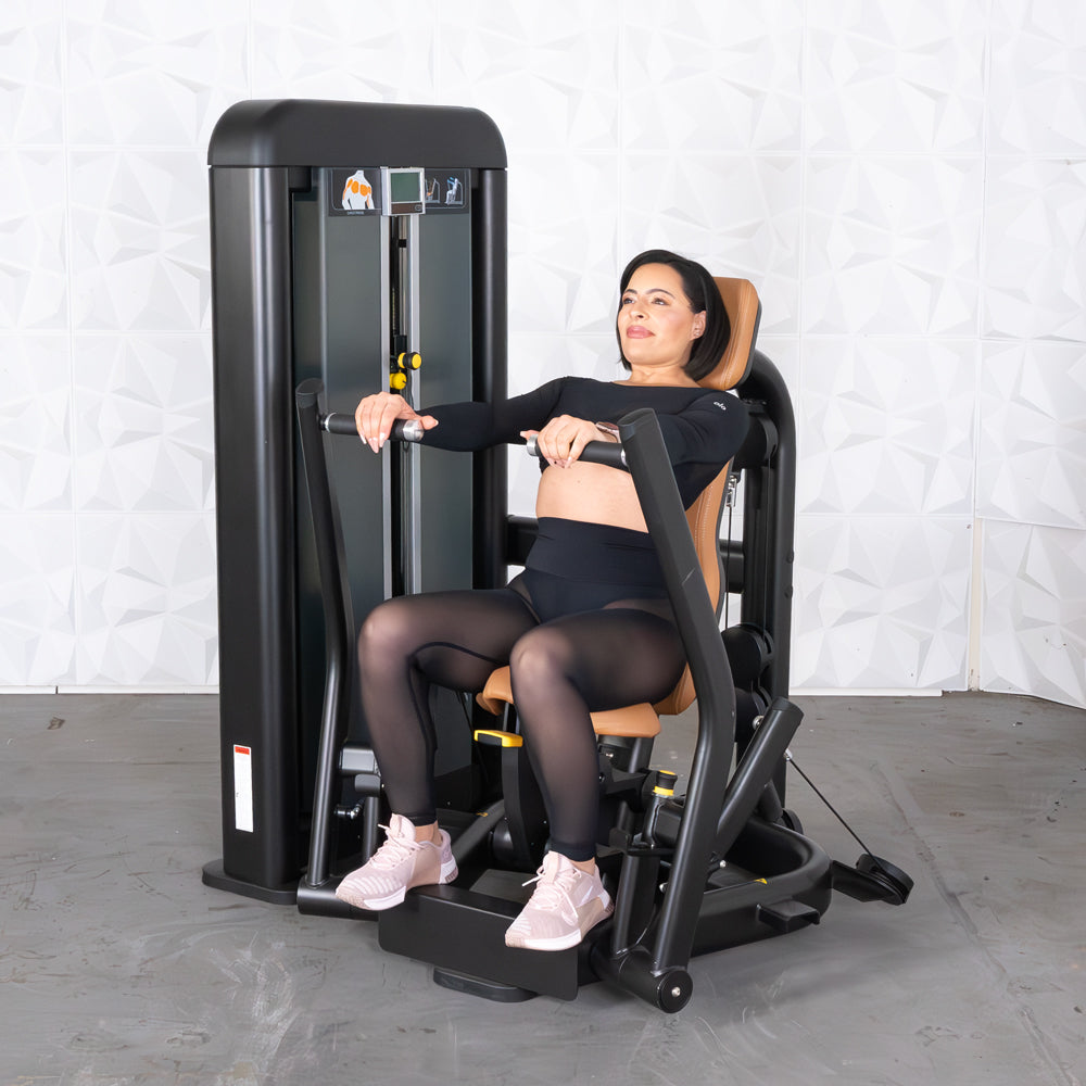 Woman using a black and brown chest press machine in a gym.