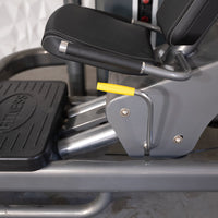 Thumbnail for Close-up of a leg press machine with black padded seat, yellow adjustment handle, and 