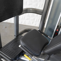 Thumbnail for Close-up of a leg press machine with black footplates and padded seats, showing the 