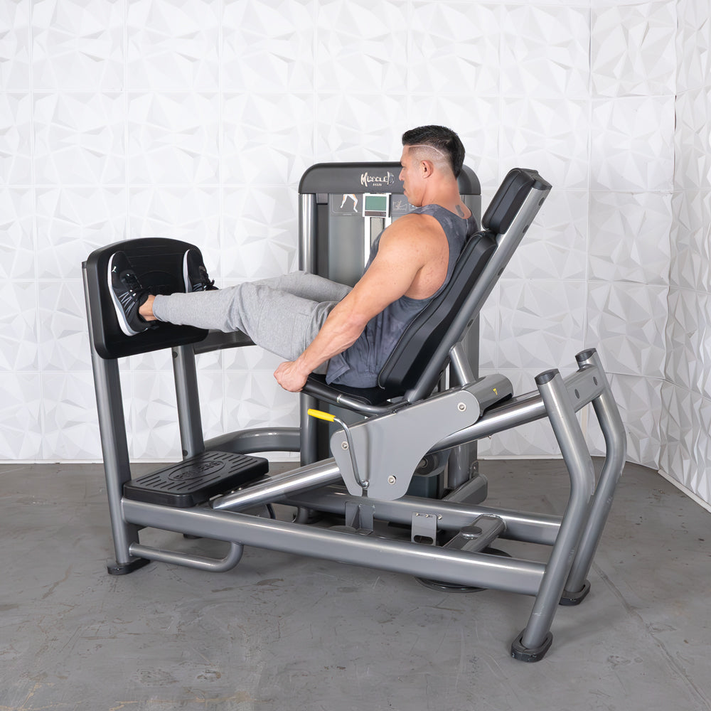 Man using a gray leg press and calf raise machine with black pads in a gym.