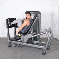 Thumbnail for Man using a gray leg press and calf raise machine with black pads in a gym.