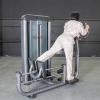 Thumbnail for Woman using a gray glute blaster machine in a gym, extending her leg back.