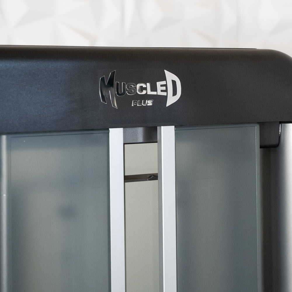 Close-up of the "Muscle D Plus" logo on a black fitness machine, with frosted panels below.
