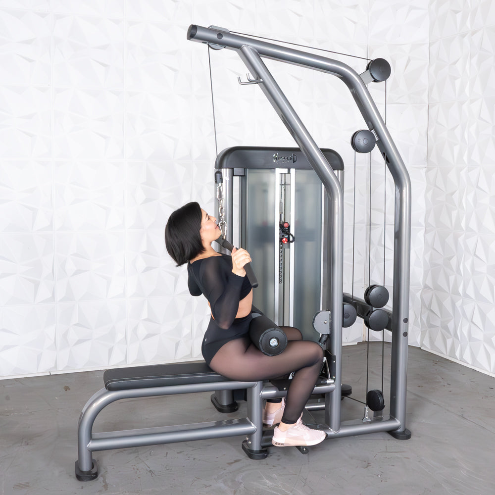 Woman performing a lat pulldown on a gray and black commercial fitness machine.