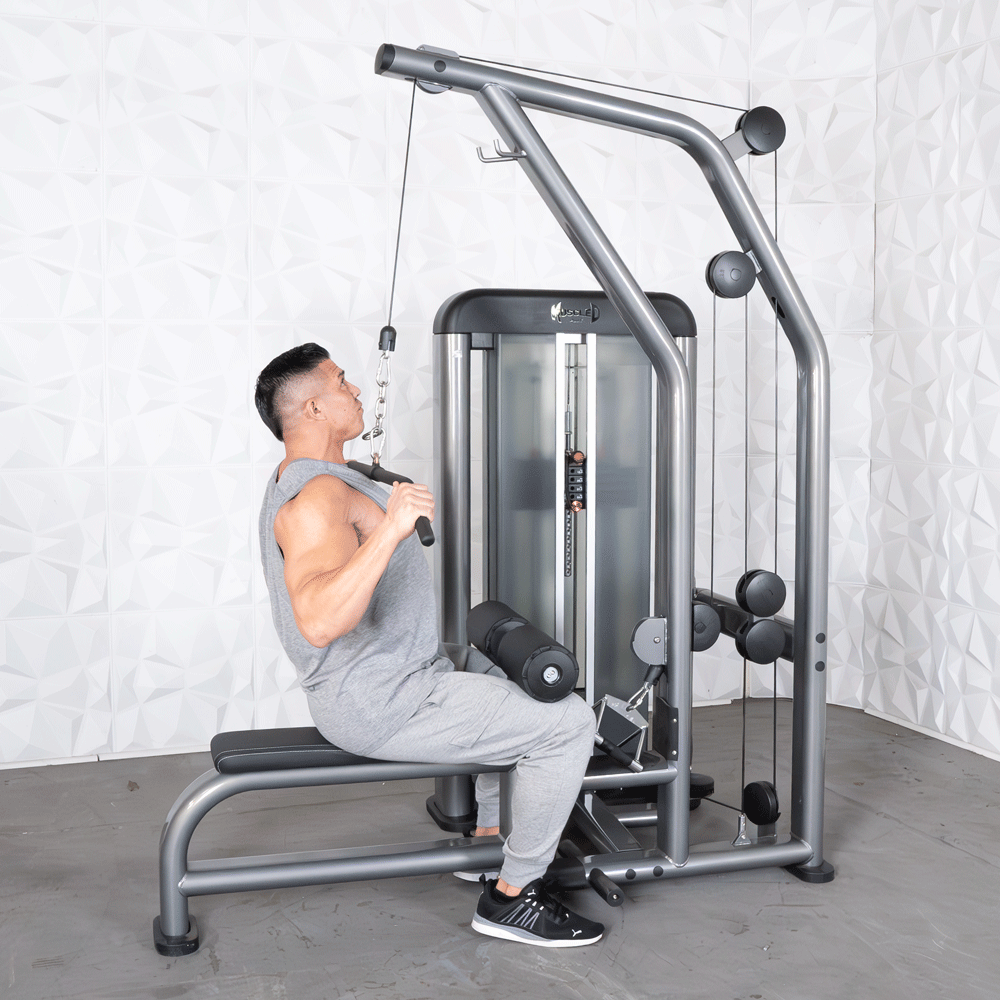 Man in gray tank top and sweatpants using a gray lat pulldown machine with a black seat and leg pads.