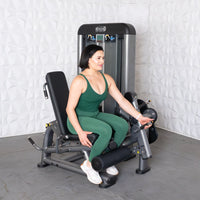 Thumbnail for Woman in green activewear seated on a leg extension/curl machine, adjusting the settings.