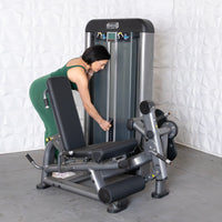 Thumbnail for Woman in green adjusting weights on a gray leg extension curl combo machine.