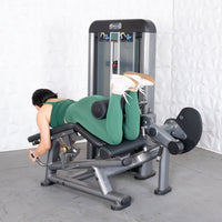 Thumbnail for Woman in green using a leg extension curl combo machine, performing a leg curl.