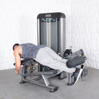 Thumbnail for Man performing leg curls on a gray and black fitness machine.