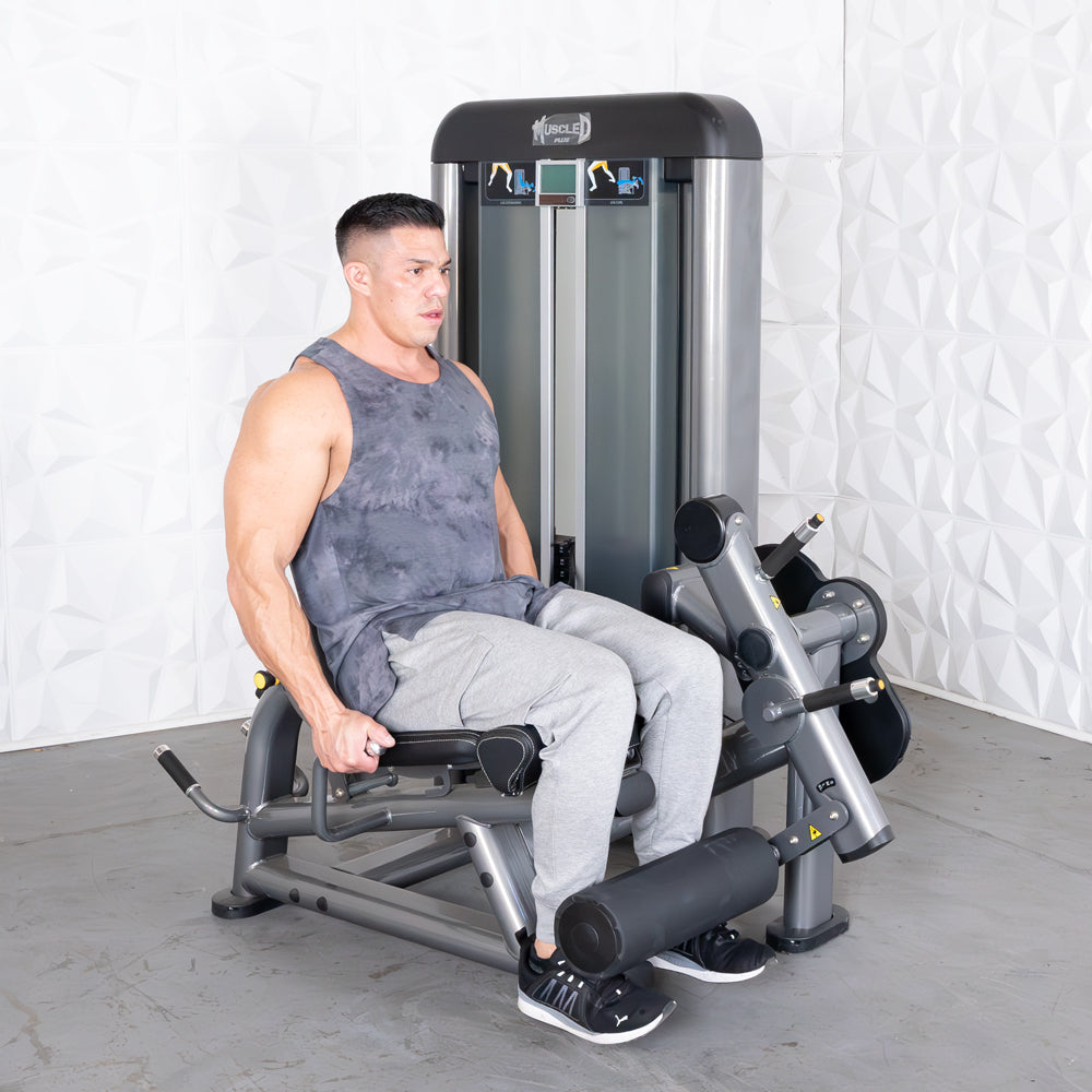 Man using a gray leg extension curl combo machine in a gym.