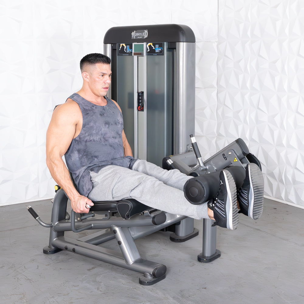 Man using a gray leg extension curl combo machine in a gym.